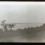 View of a wide river with a distant canoe boat in the middle