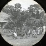 Locals dancing in front of a straw-roofed house