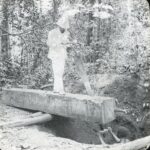 A missionary and local using a 2-man saw to cut a large wooden block into planks