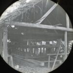 A simple wooden boat being constructed in a low covered shed