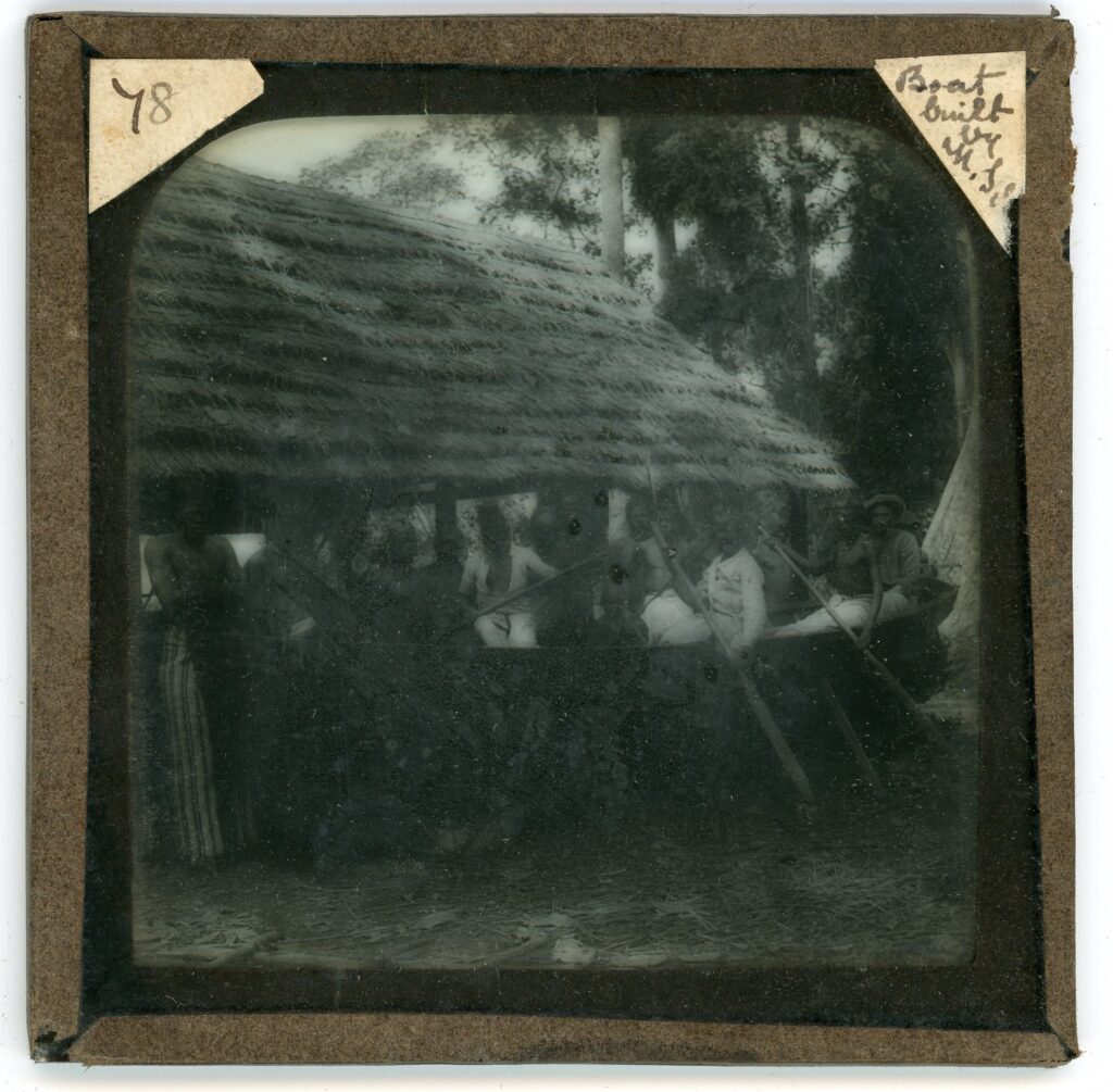 A built wooden rowboat beside a boat building shed