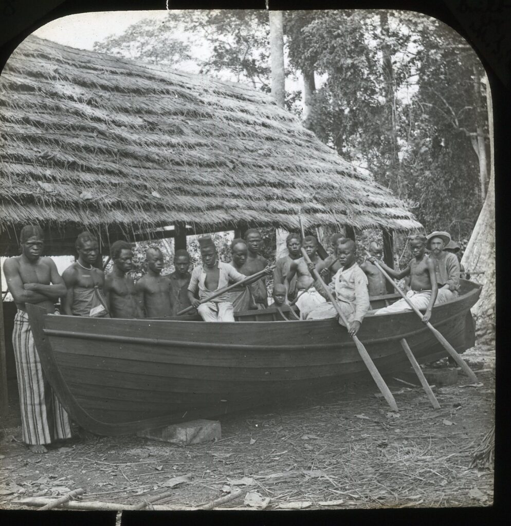 A built wooden rowboat beside a boat building shed