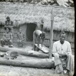 Locals dressing and kneading each others' hair outside a hut