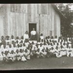 A group of local children assembled outside a simple plank schoolhouse