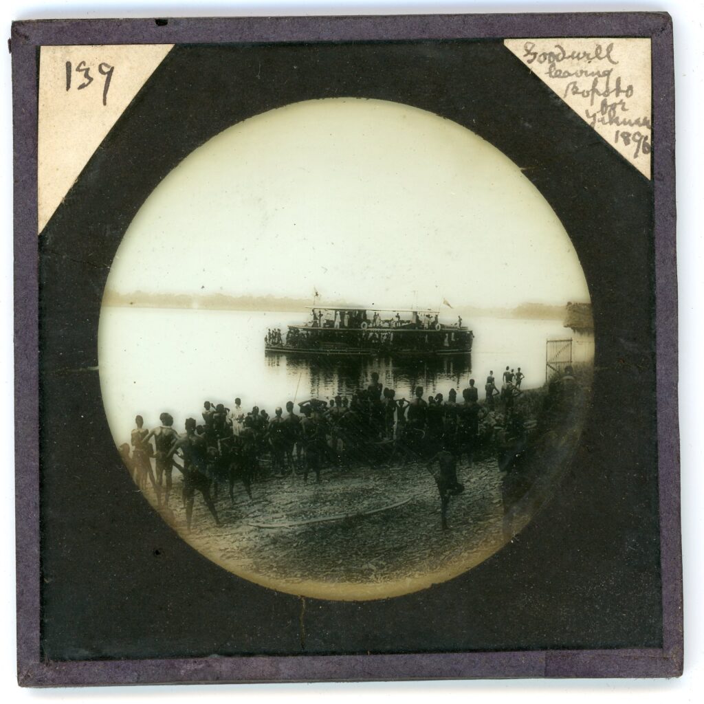 A paddle-steamer ship leaving with locals assembled on the riverbank