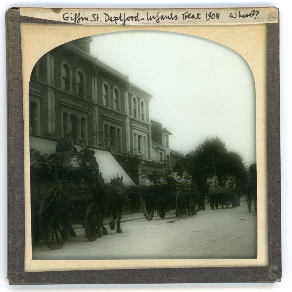 Slide showing a procession of simple horse-drawn carriages carrying local children