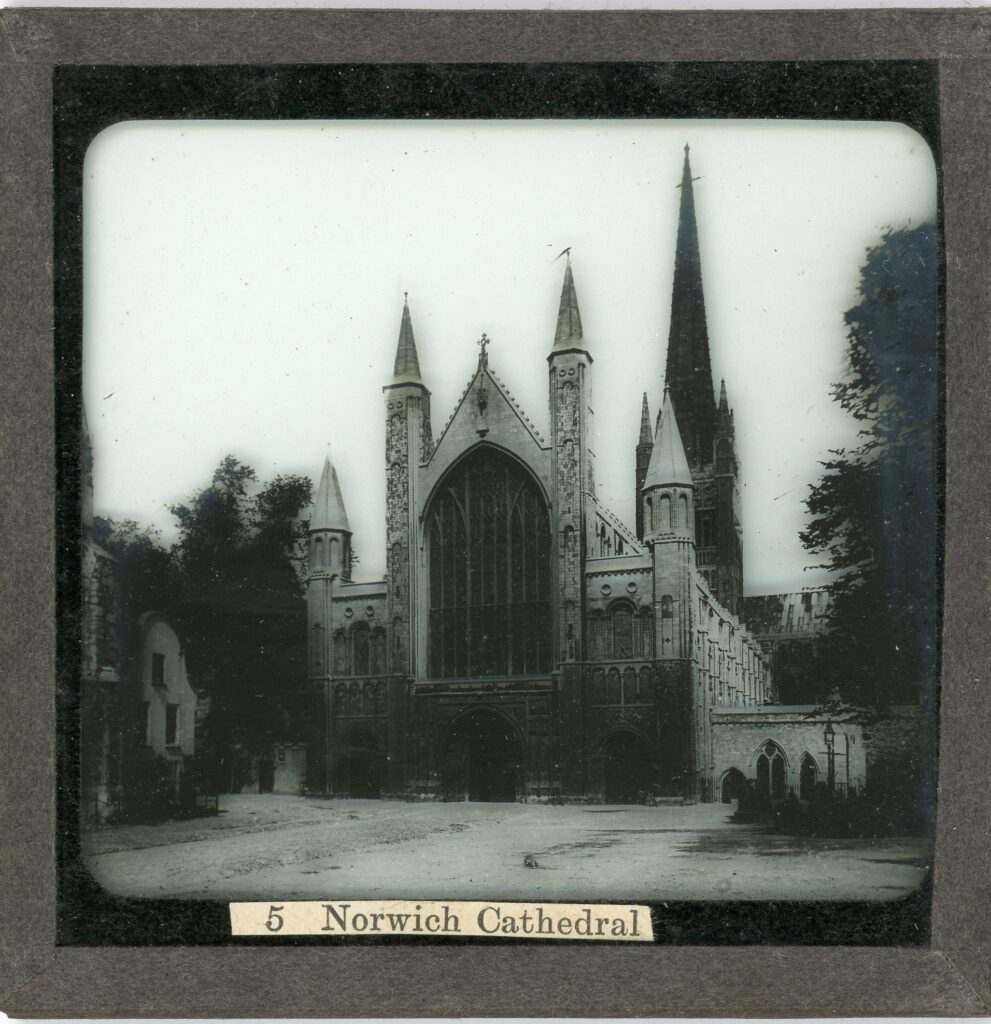 Slide showing the gothic cathedral of Norwich with large central arched window and single spired tower