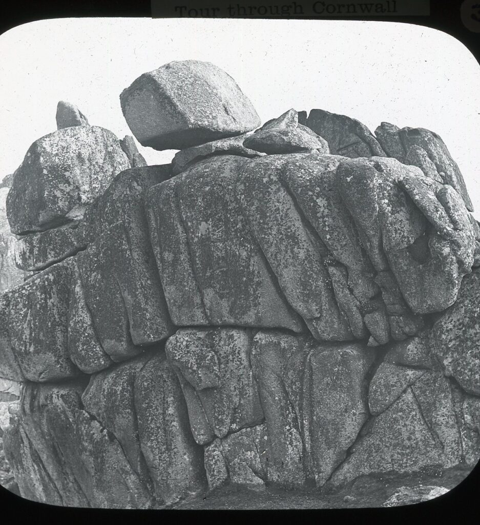 Slide showing a large boulder with smaller rocks stacked atop