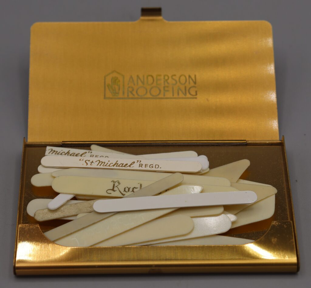 Gold-cloured metal card case containing assorted collar stiffeners