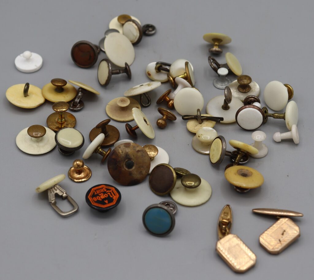 Assorted collar studs and cuff-links, spread out to show more detail