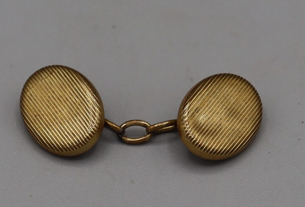 Single gold-tone oval cufflink, front view