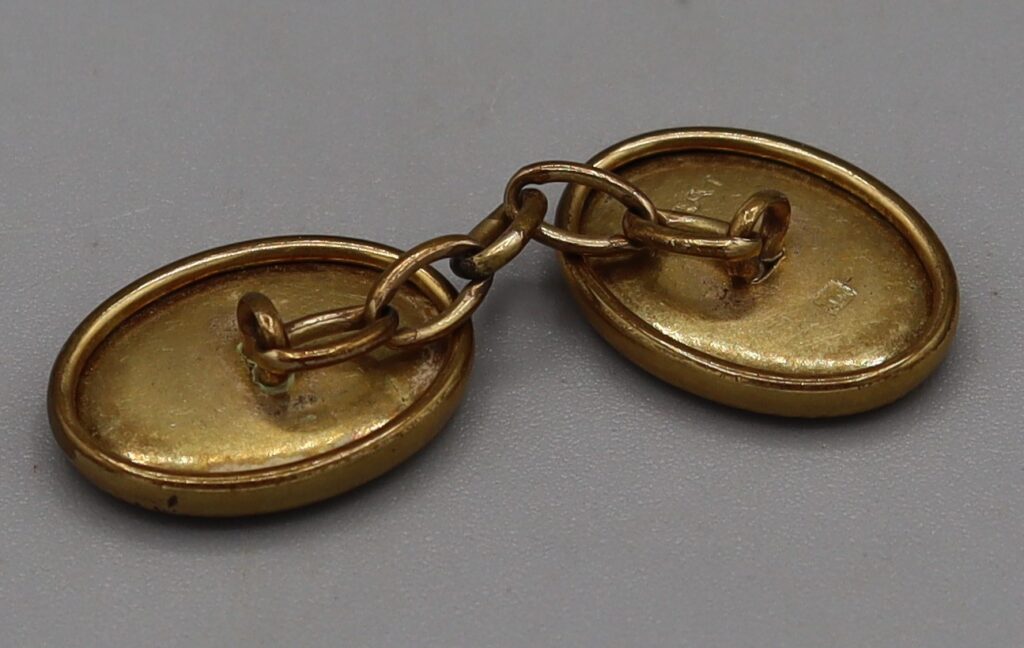 Single oval cufflink, back view showing chain links