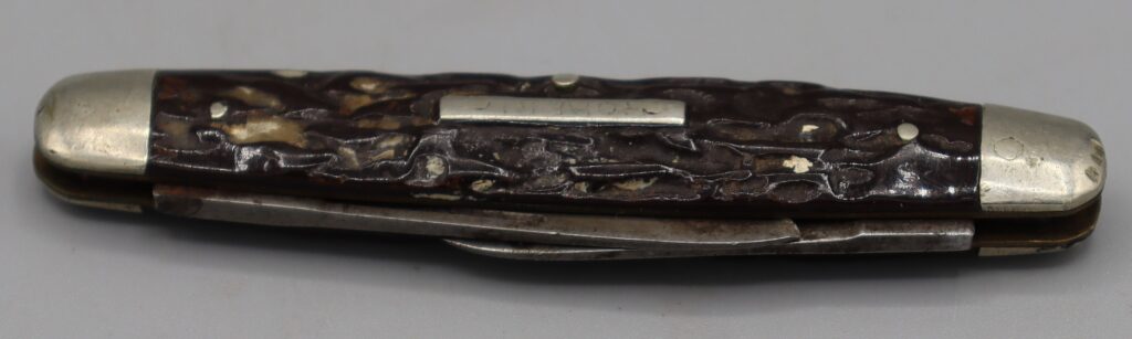 Penknife, folded, view from top showing silver metal end caps and narrow metal panel inset