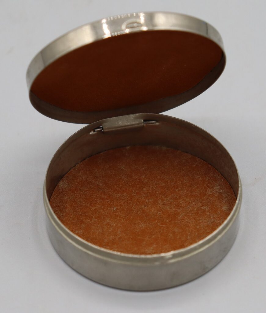 Round silver metal box shown with hinged lid open