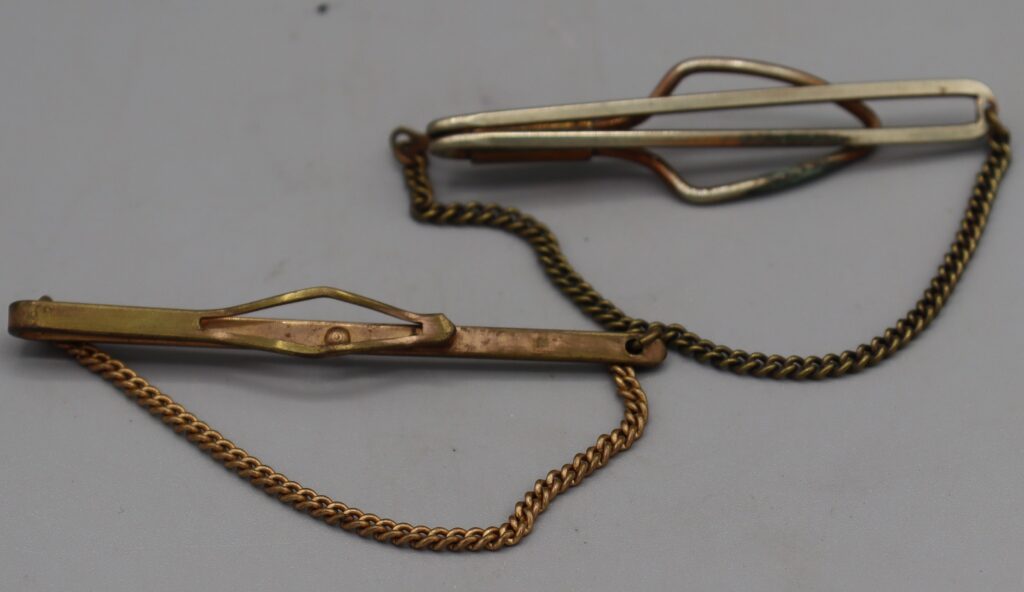 Two metal tie clips, one silver metal, one gold tone, reverse side view