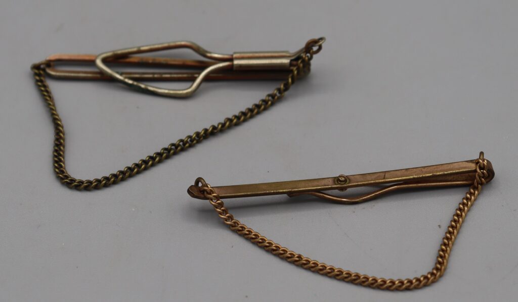Two metal tie clips, one silver metal one gold tone