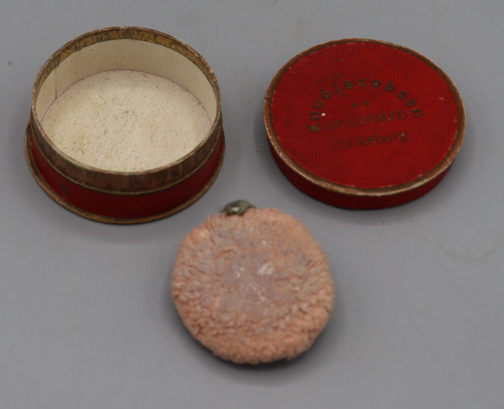 circular jewellery box with a mauve powder puff