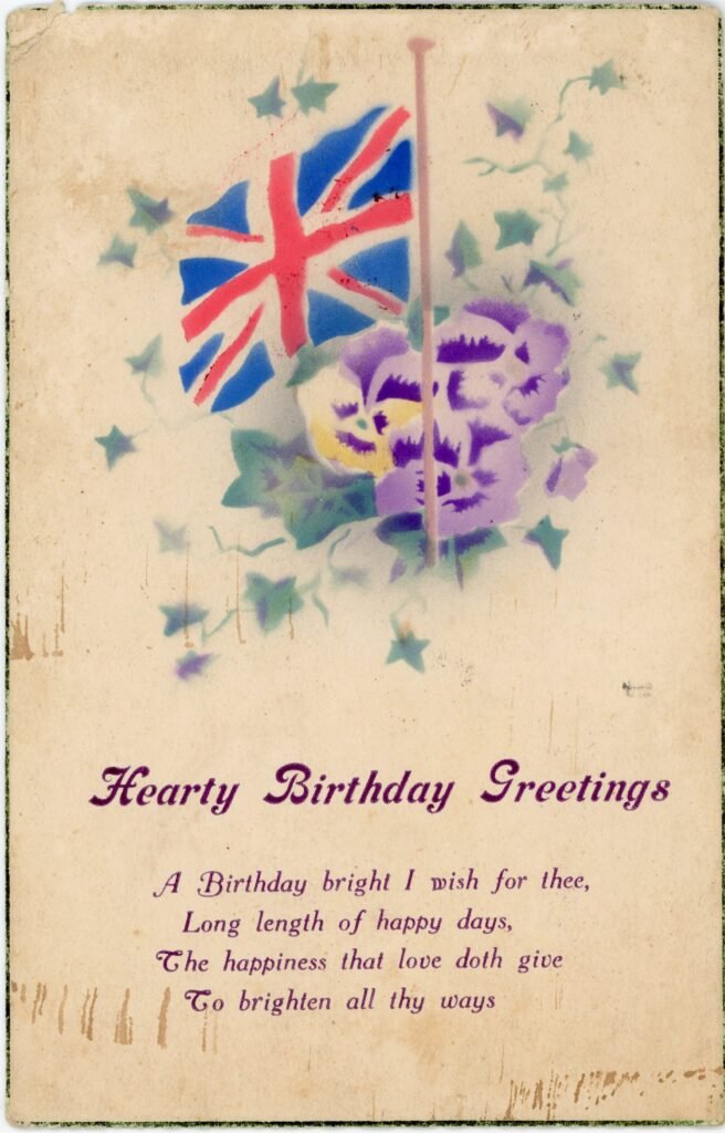 Front of an Edwardian postcard showing Union Flag above flowers with a poem for 'hearty birthday greetings'